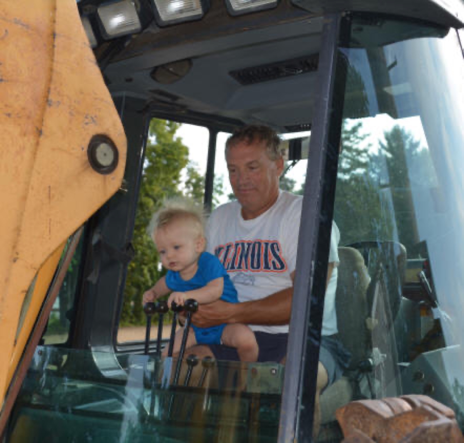 Mickey Tate with his grandson Thatcher in the cab of a backhoe